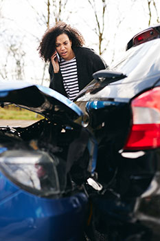 Woman calling her auto insurance company after being in a fender-bender accident