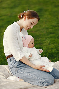 Mom holding her baby on a picnic blanket in the park