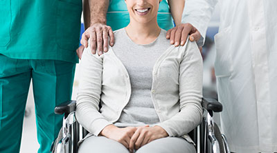 Woman with a short-term disability sitting in a wheelchair with doctors behind her