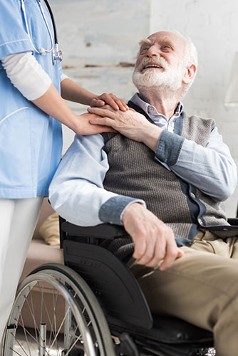 Senior man in a wheelchair getting help from a long-term care nurse