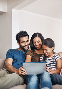 Happy family of three sitting on the couch looking up term life insurance quotes