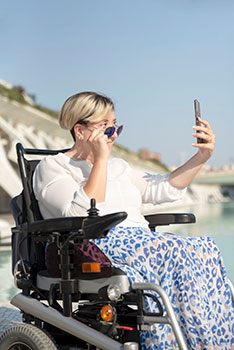 Woman with a disability in a wheelchair taking a selfie at the beach